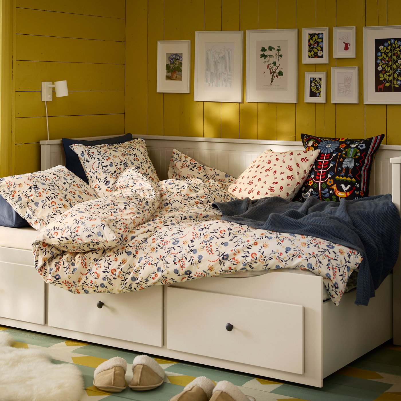 En Vit HEMNES-bäddsoffa i gästrummet med gula träväggar.