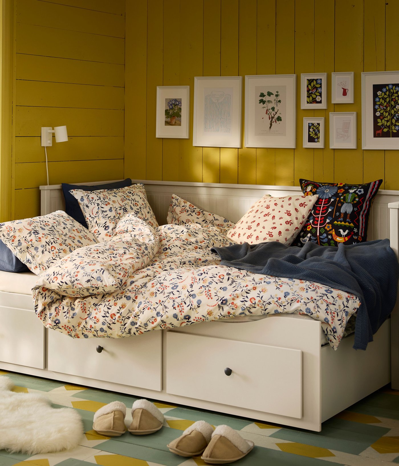En Vit HEMNES-bäddsoffa i gästrummet med gula träväggar.