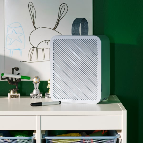 An UPPÅTVIND air purifier in blue, placed on a white desk in a children’s room with green walls and a hand-drawn bunny.