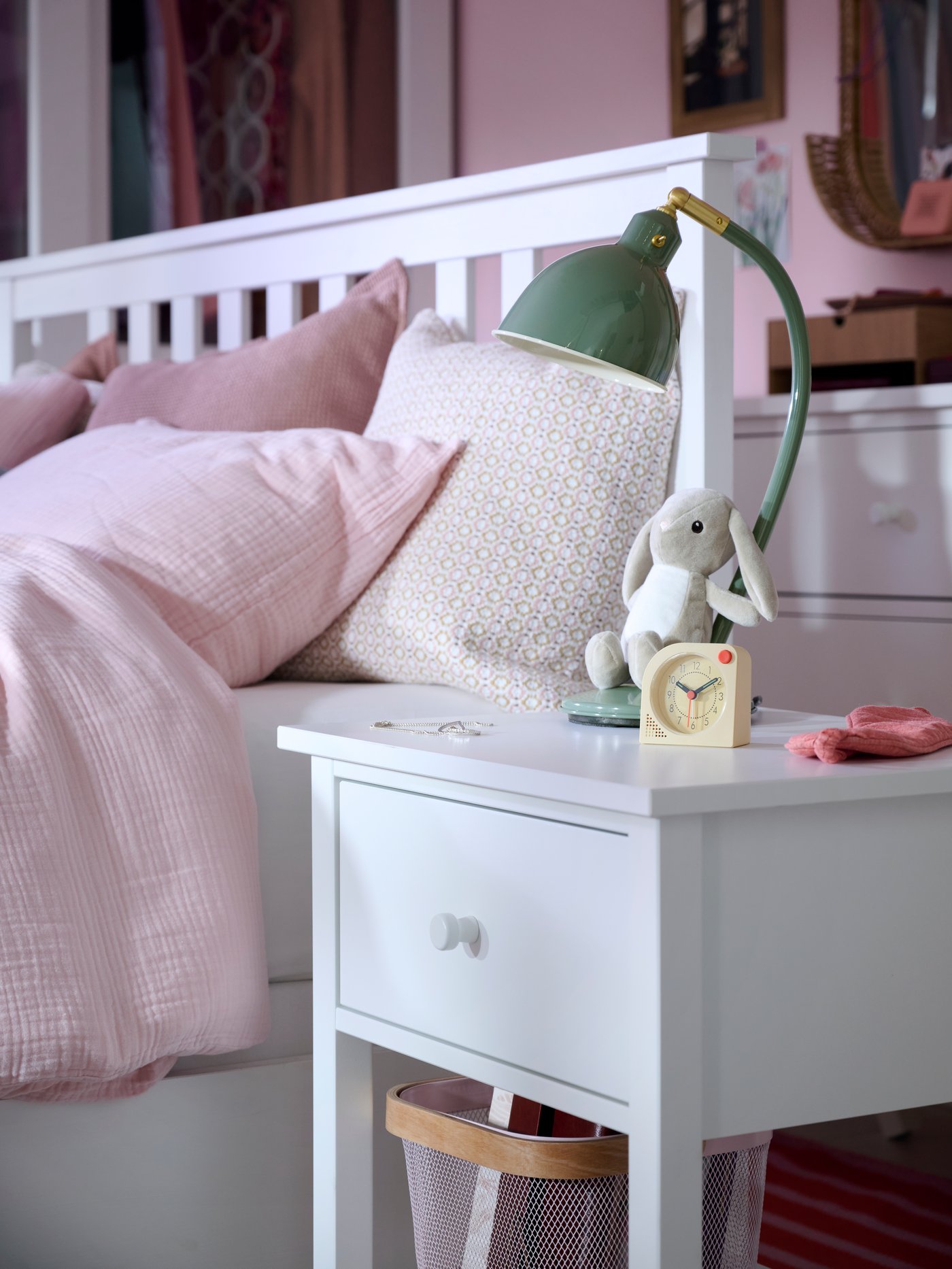Close-up of bedside table with TJINGA alarm clock, DVÄRGHARE soft toy rabbit and RÖDFLIK desk lamp.
