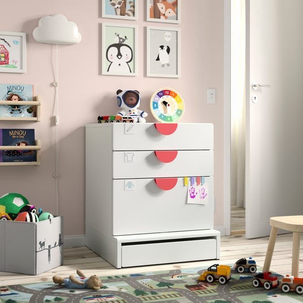 Room with a white storage drawer unit in the middle and toys all around it.