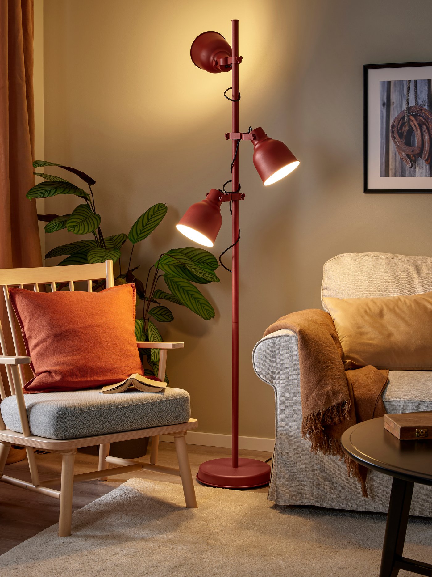 Red HEKTAR floor lamp with three spotlights illuminating the wall, the sofa and an armchair 