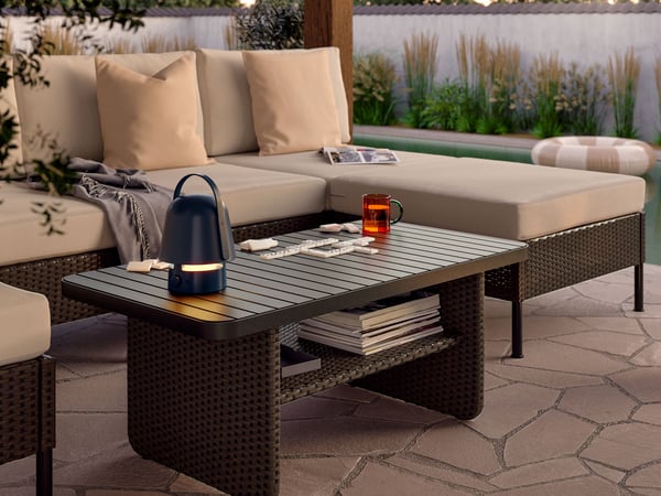 A couch in the garden, with a table and Bluetooth lamp