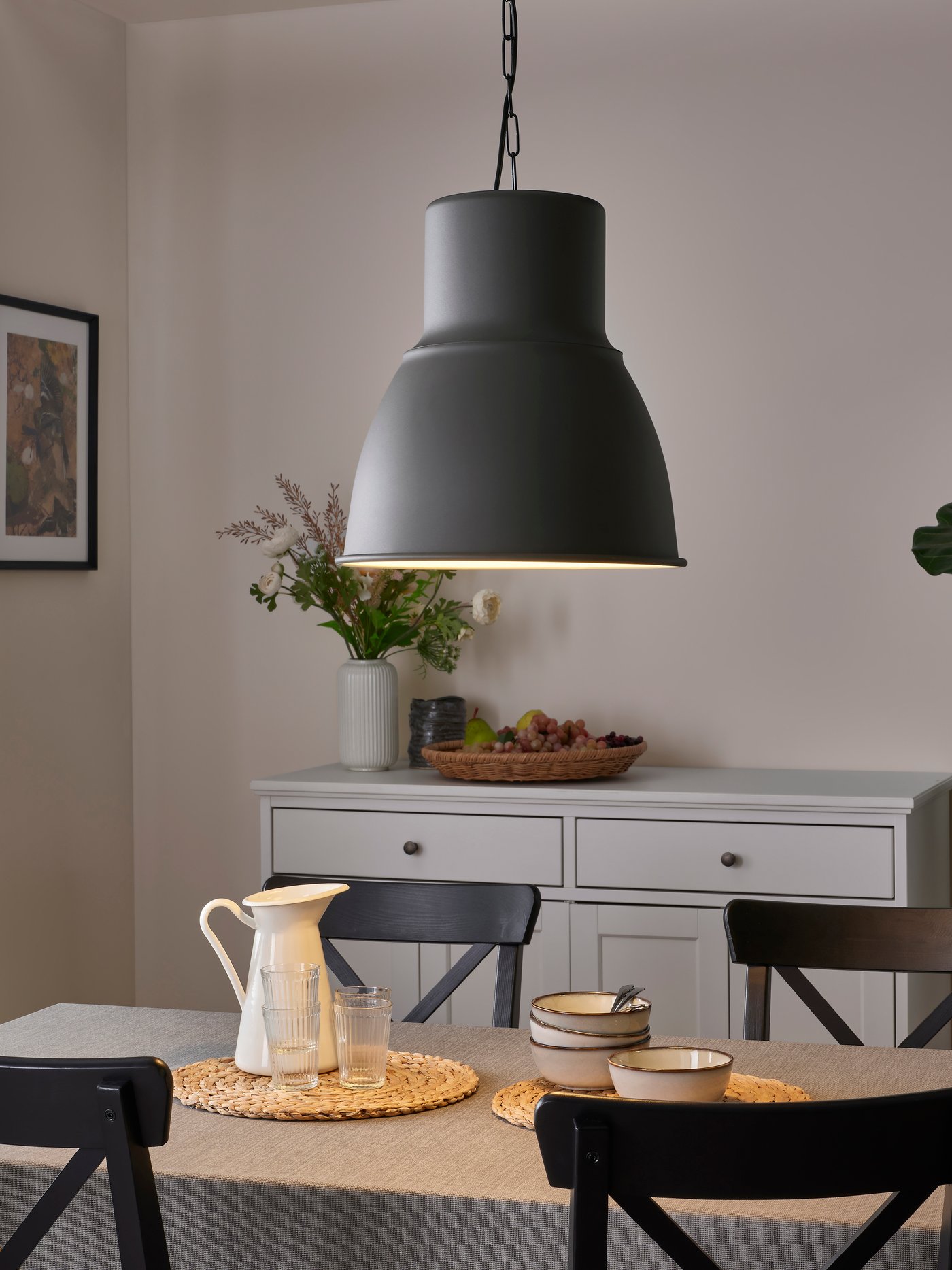 Eine dunkelgraue HEKTAR Pendelleuchte hängt über einem Esstisch