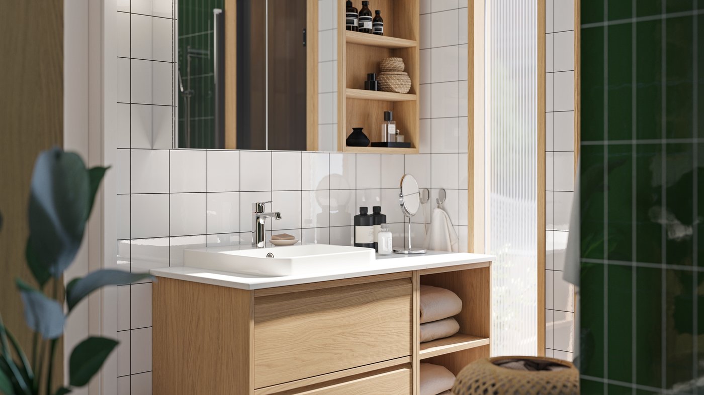 A bathroom with ÄNGSJÖN fronts in oak effect has a vanity with open and closed storage and a mirror cabinet above it.