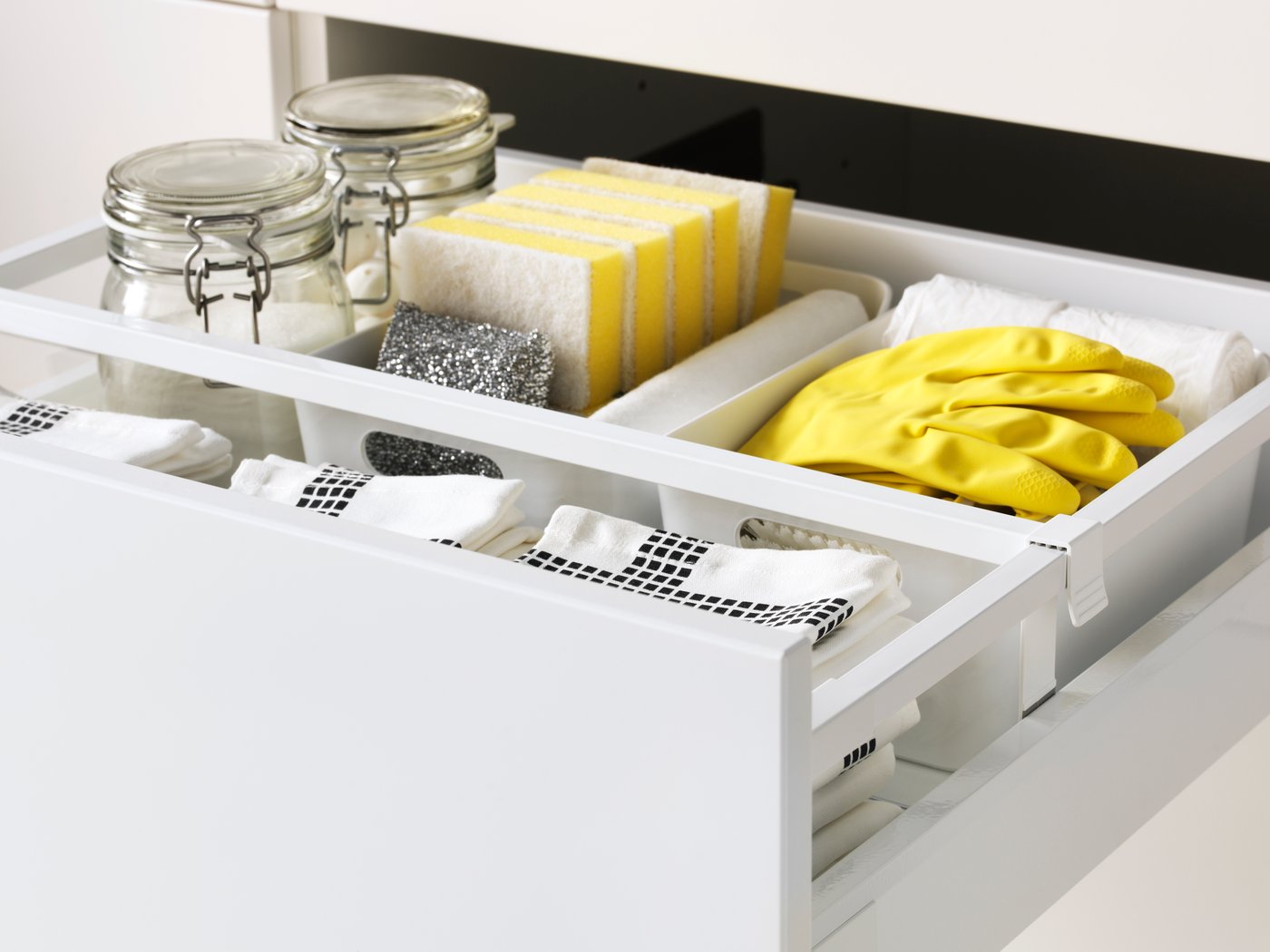 Cleaning products and yellow rubber gloves in a kitchen drawer.