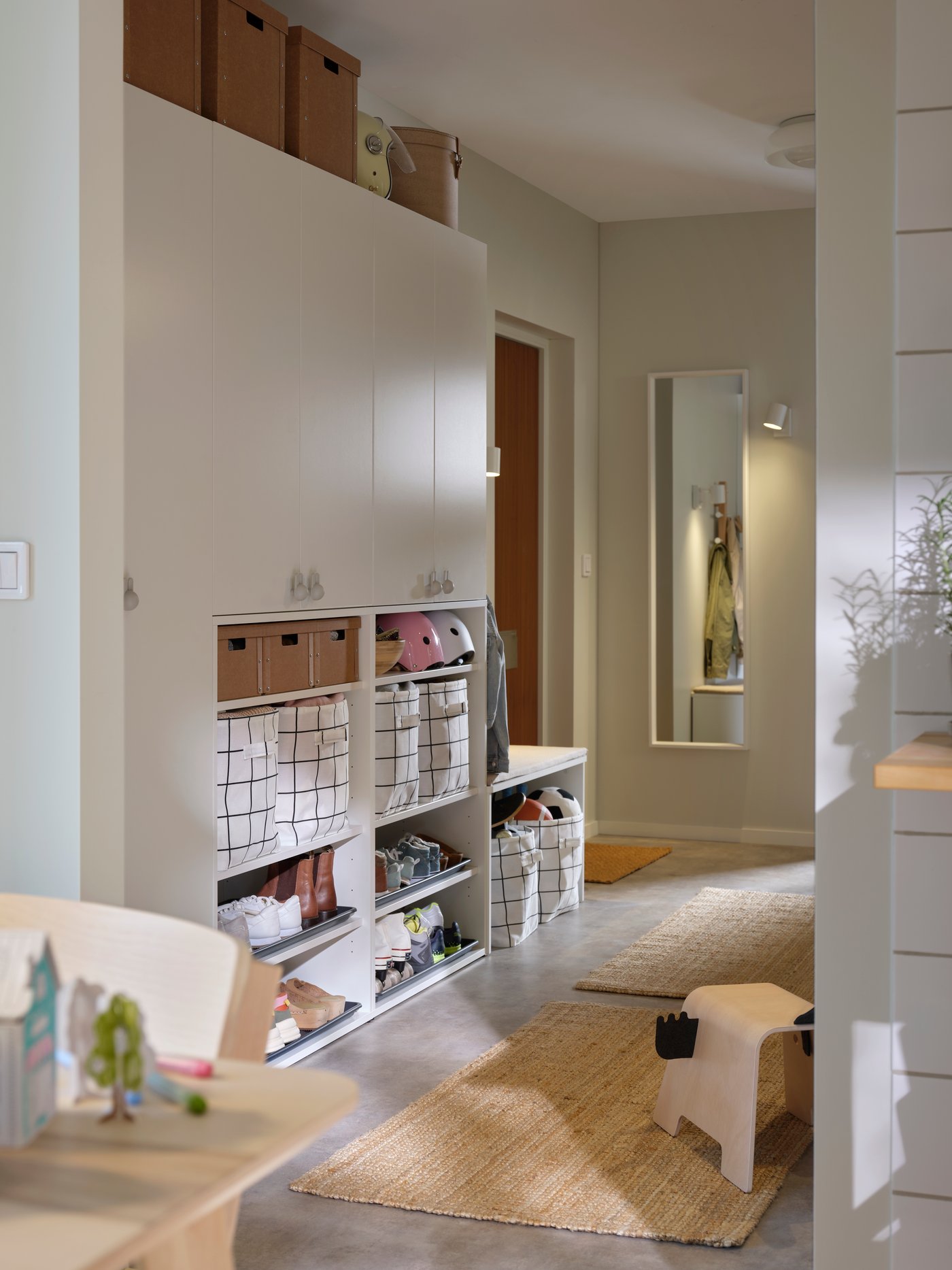 A hallway with storage cabinets and baskets leading to a wall where the NISSEDAL mirror is mounted beside a doorway.