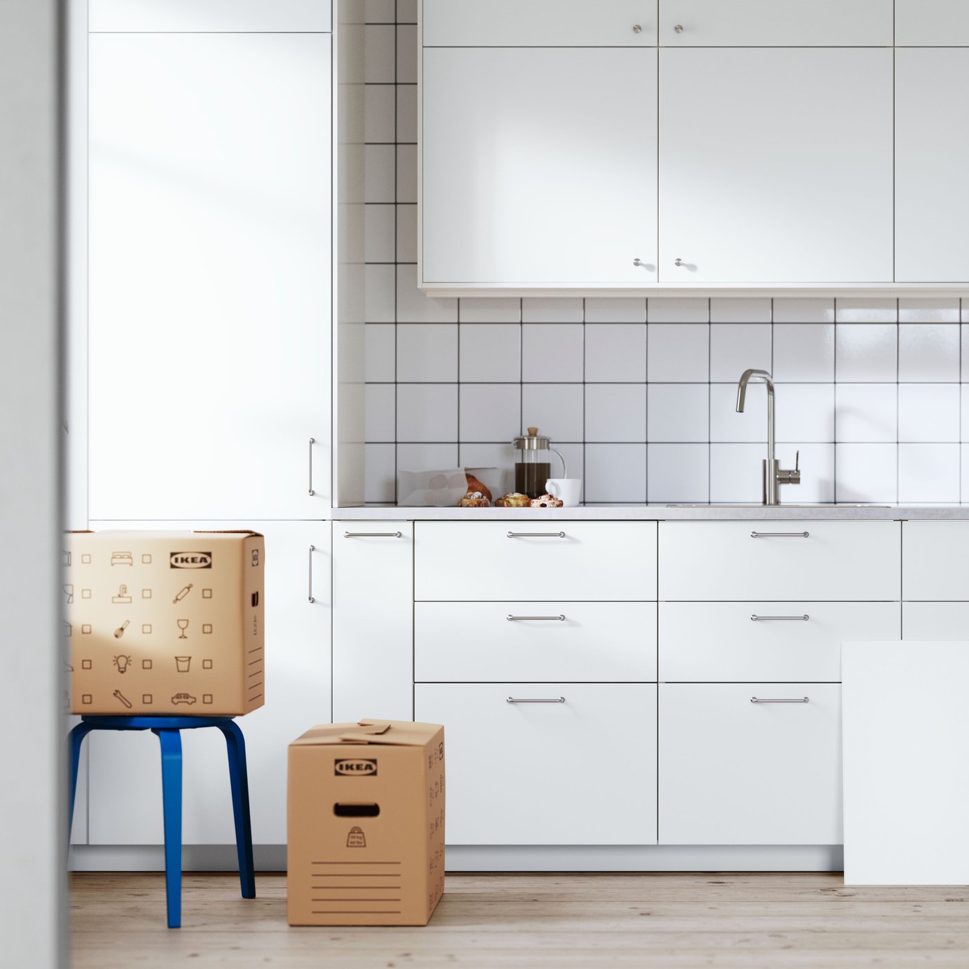 A white METOD kitchen in the last stages of installation. A drawer sits on the floor and its front leans against a cabinet.