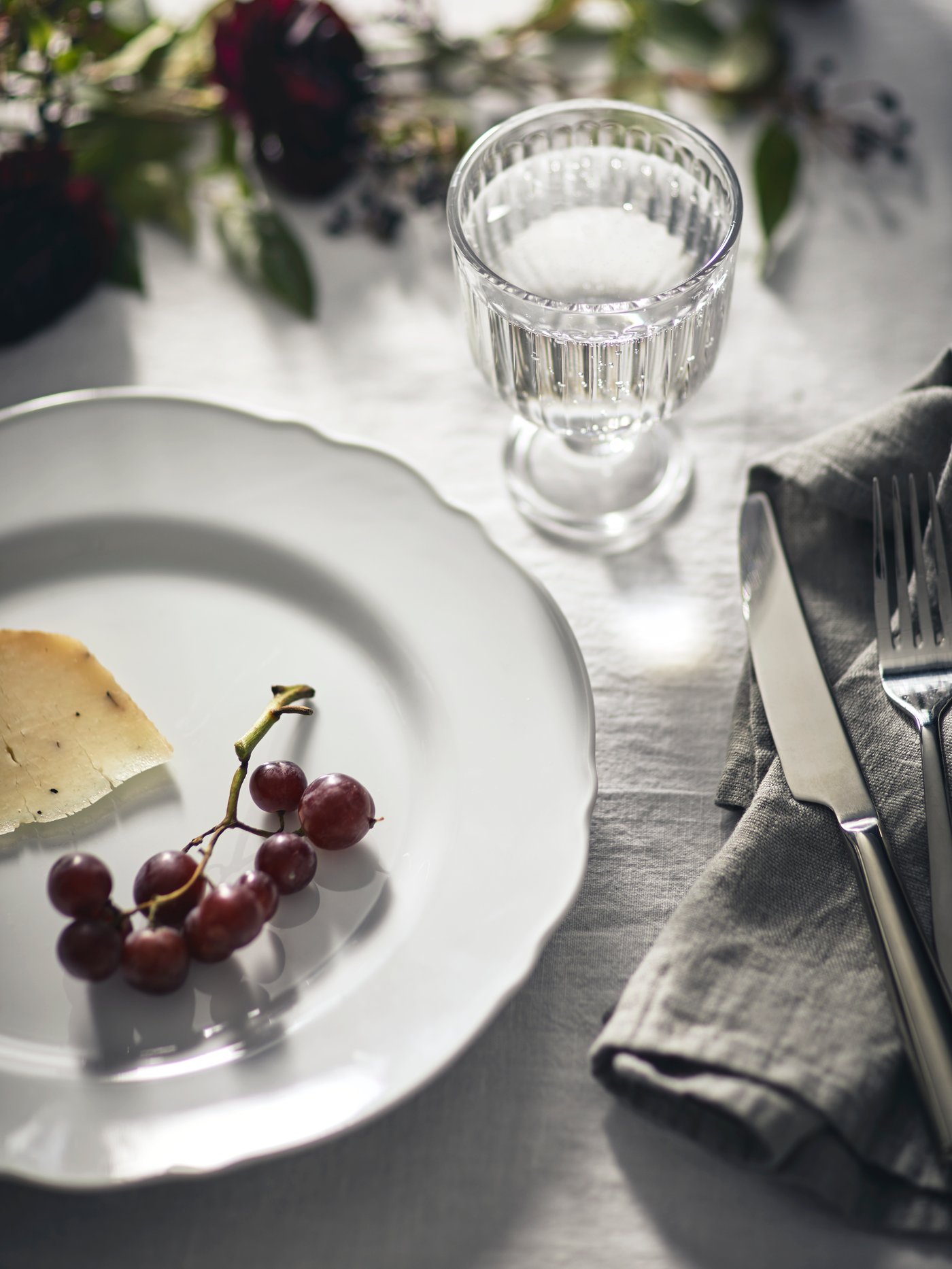 A table is set with rustic dinnerware and cut flowers can be seen in the back ground