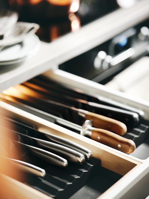 Keukenlade met een georganiseerd messenblok-inzet toont een reeks scherpe messen met houten en metalen handvatten