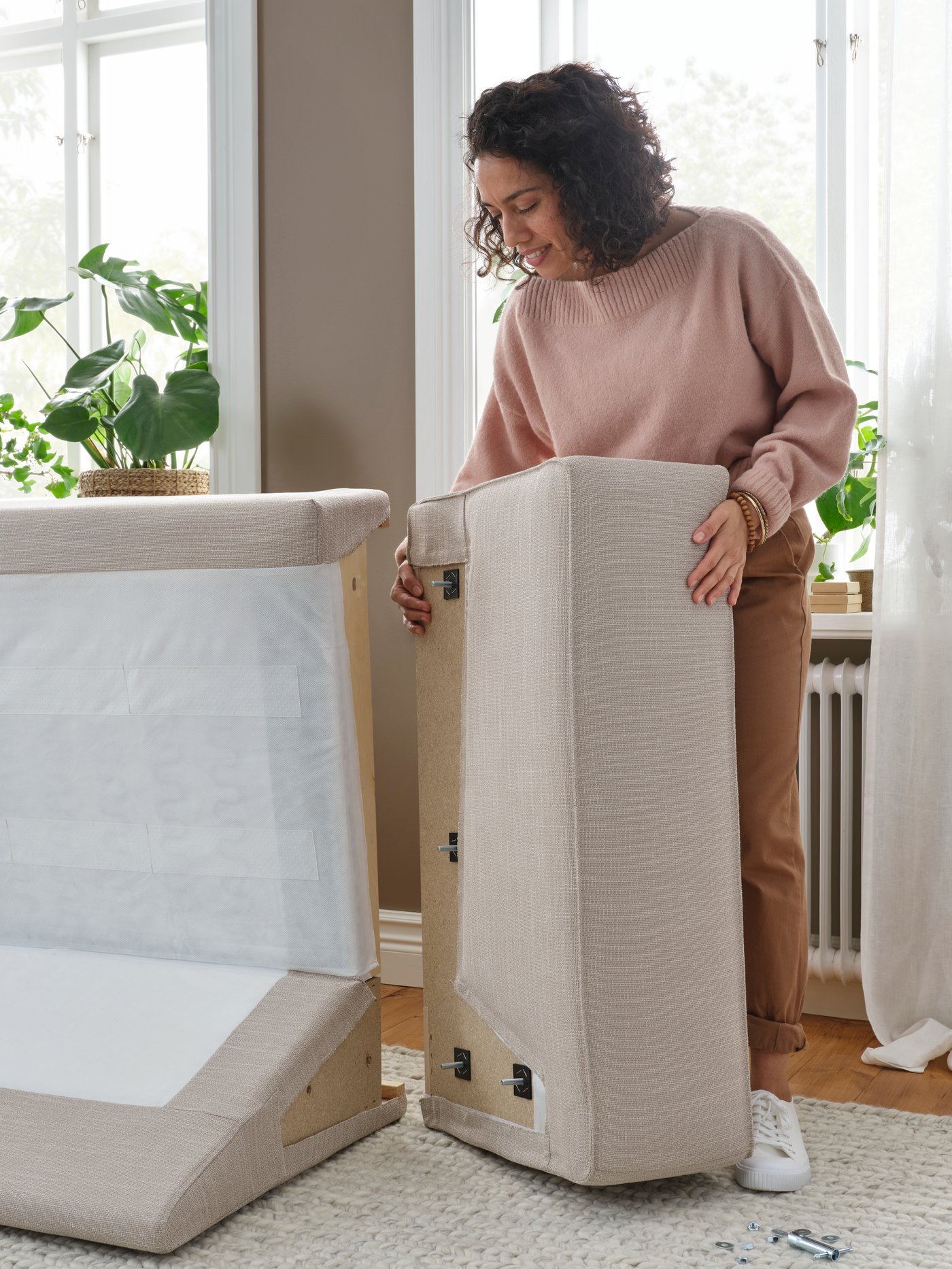 Kobieta montująca bok sofy w beżowym pokryciu do modułu oparcia.