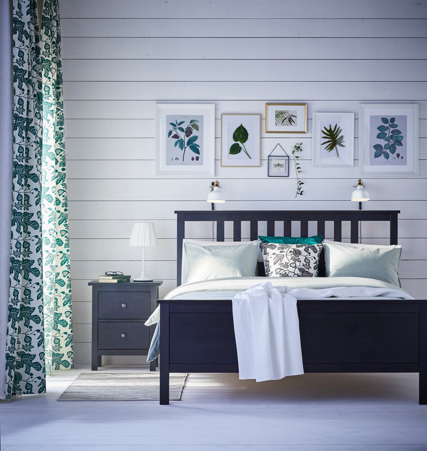 A Swedish white bedroom with black bed and green curtains