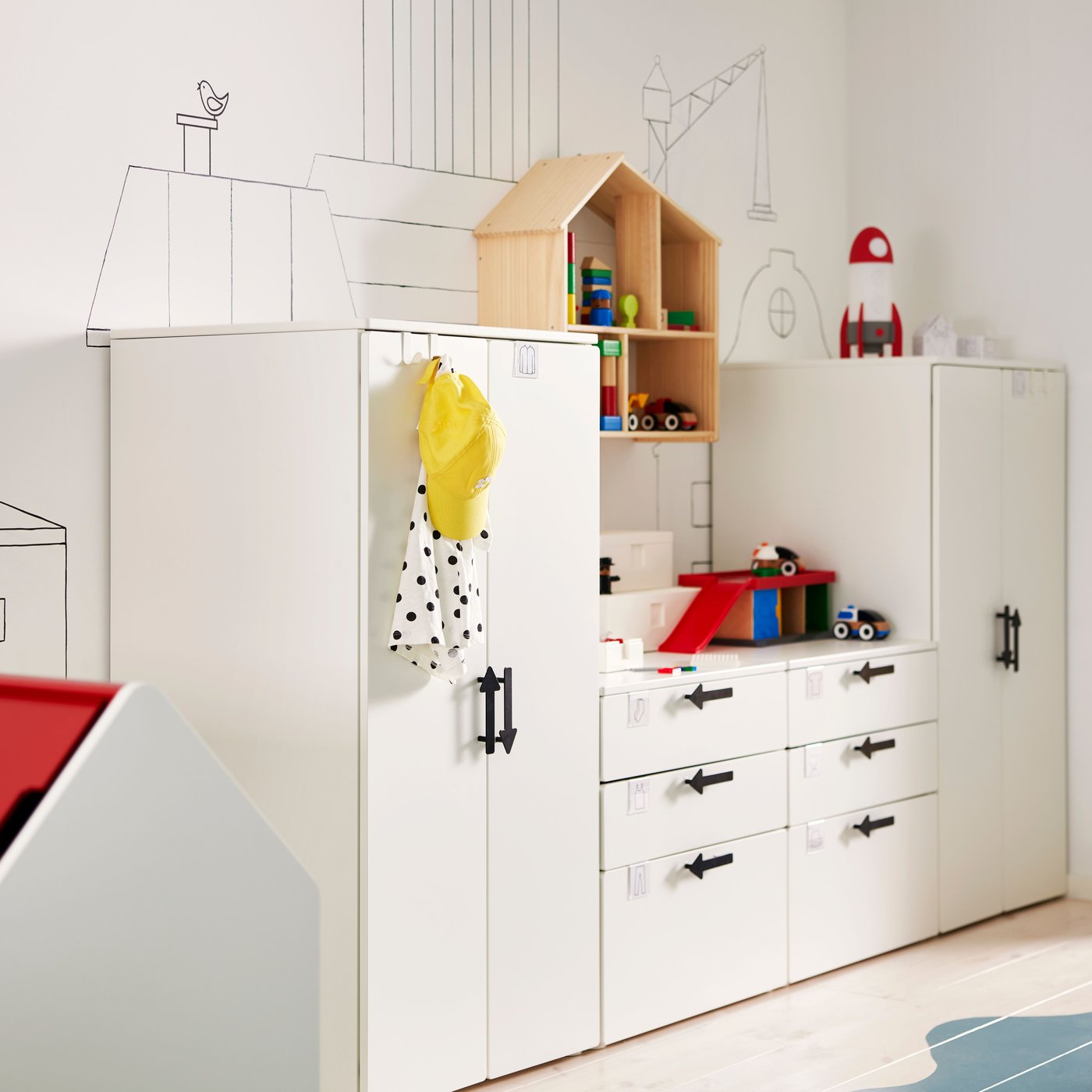 Vita SMÅSTAD/PLATSA förvaringsenheter med JÄRNSPARV svarta handtag mot en vägg med ett FLISAT dockskåp/hylla på.