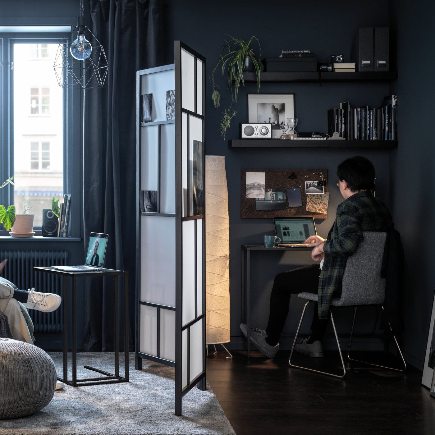 Soggiorno diviso a metà da un paravento RISÖR e, su ciascun lato, una persona davanti a un computer.
A destra, la persona è suduta su una poltrona e accanto ci sono pouf SANDARED e un tavolino BURVIK. A sinistra, un uomo è seduto su una sedia LILLÅNÄS.