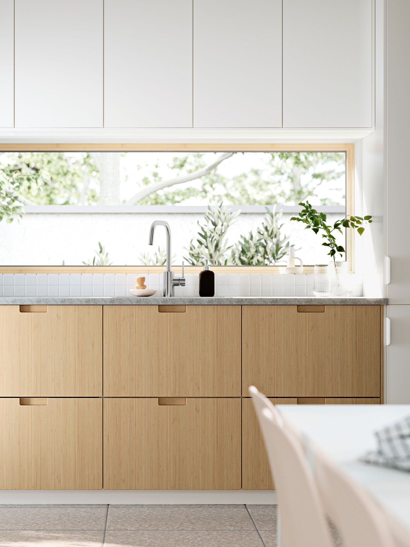 Eine Küche mit weißen grifflosen Hängeschrank mit VEDDINGE Fronten und Küchenzeile mit FRÖJERED Fronten in Bambus Optik.