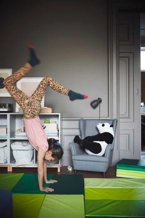 Iemand doet aan yoga in de woonkamer op een groen vloerkleed.