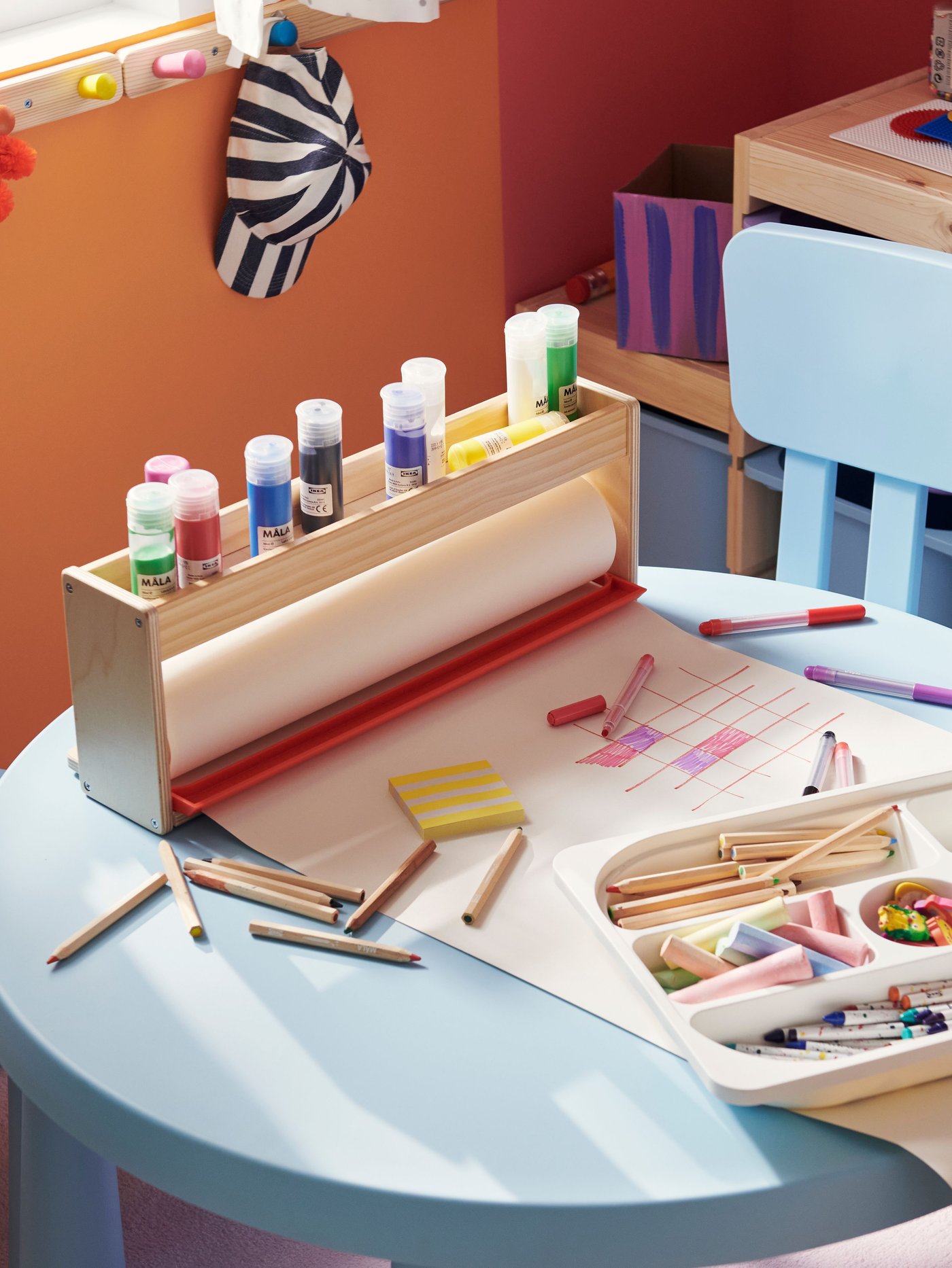 Two children’s chairs and a children’s table from the MAMMUT series in light blue. Art materials are laid out on the table.