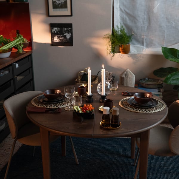  Un tavolo da pranzo rotondo in legno apparecchiato per una cena intima a lume di candela.