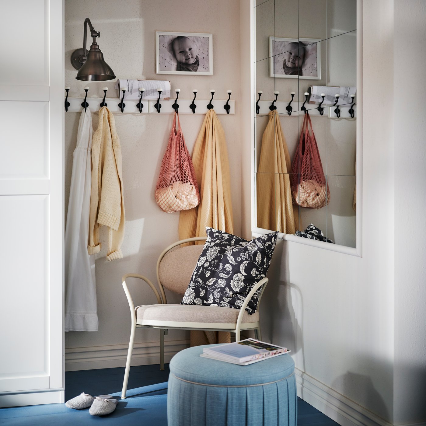 A grey-beige ISMANTORP armchair in the corner of a room with a blue ÅTERLÖGA pouffe with storage in front with a book on top.