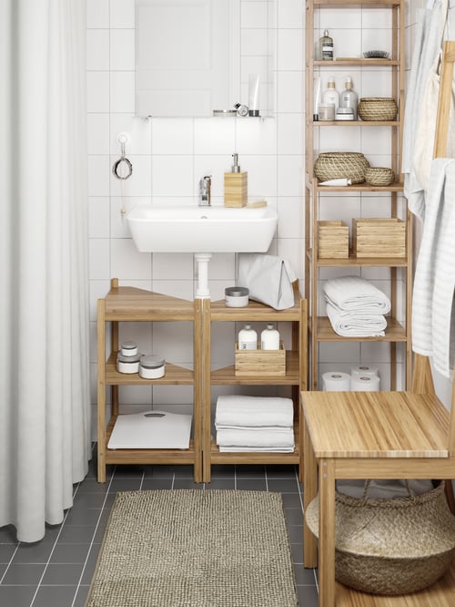 Bathroom with shower curtain, rug, corner shelves, chair with towel rack, shelving unit, towels, wash-basin, basket, mirror.
