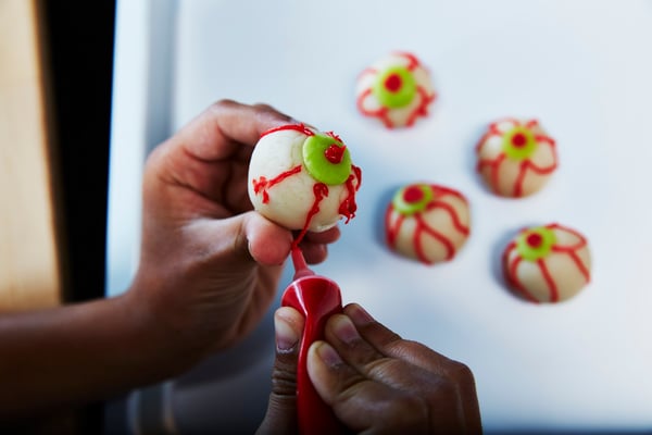 Two hands  decorating fake eyes with red coloring