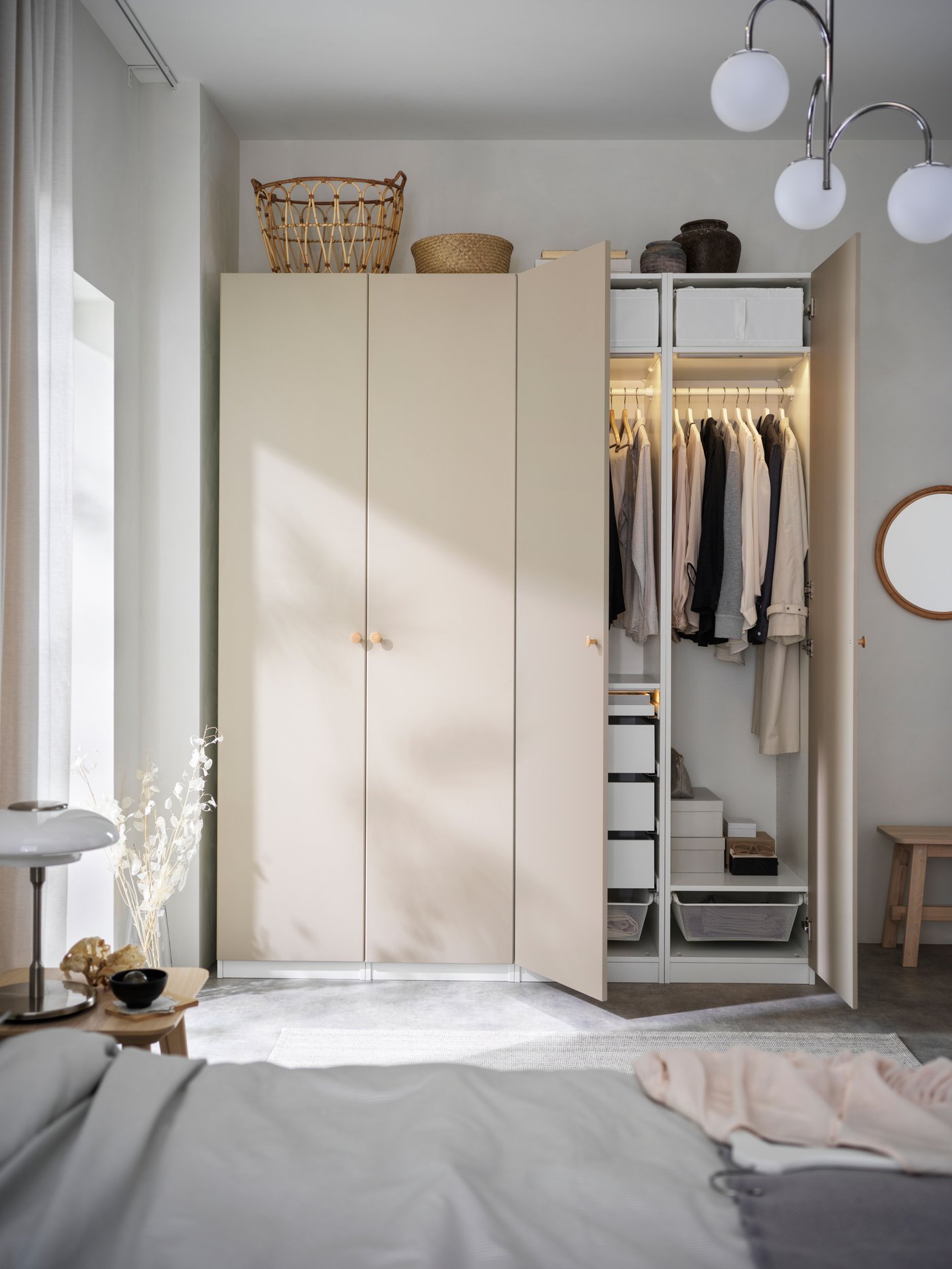 Geöffneter Kleiderschrank in einem Schlafzimmer mit beige Fronten, hängender Kleidung und integrierter Beleuchtung.