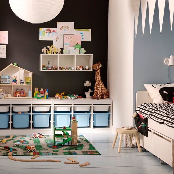 A children’s room full of toys, with a black wall and TROFAST storage system along that wall and SLÄKT bed to the right.