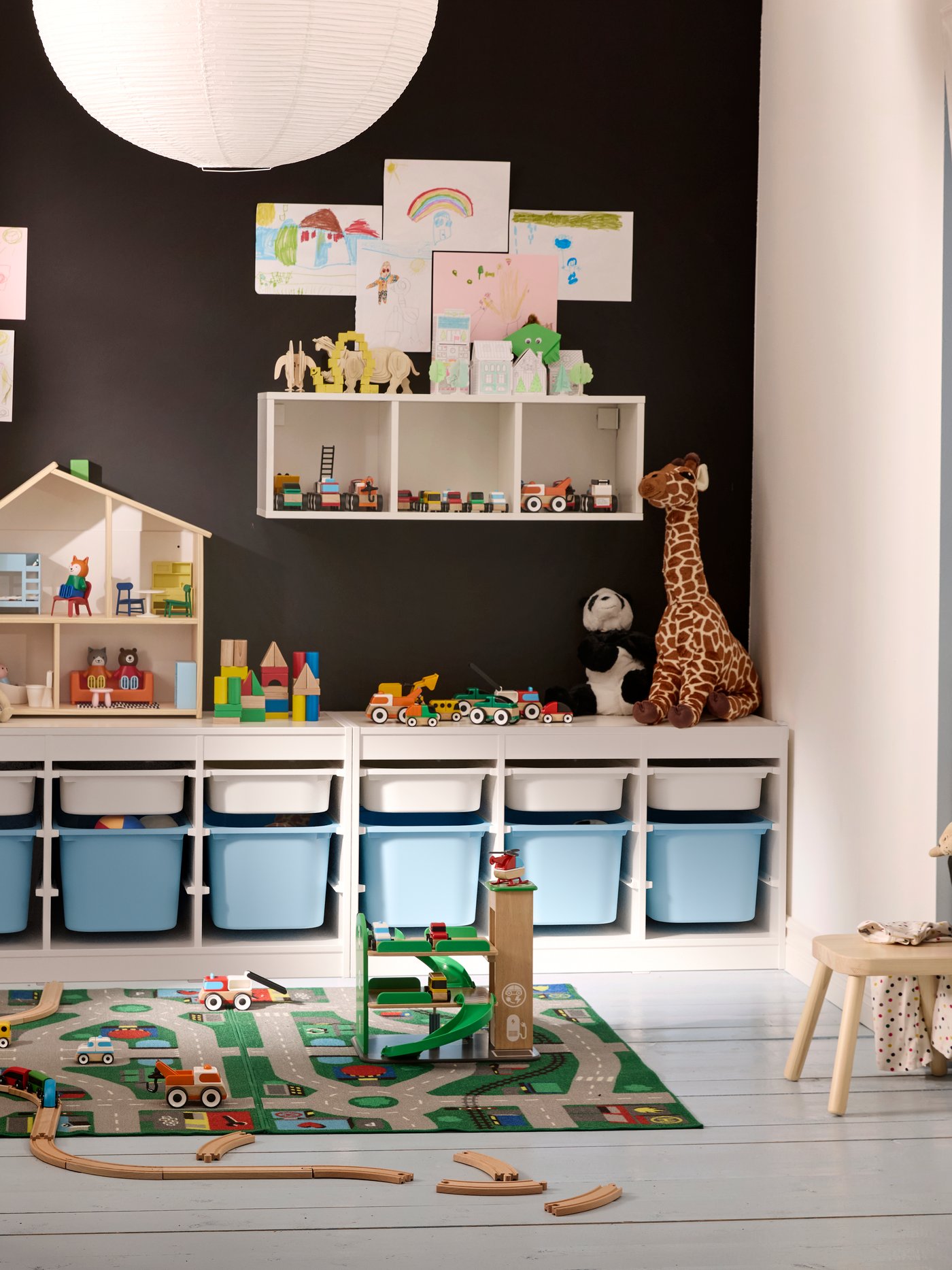 A children’s room full of toys, with a black wall and TROFAST storage system along that wall and SLÄKT bed to the right.