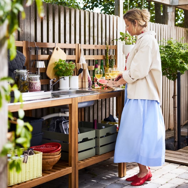 An outdoor kitchen area features a light brown stained NÄMMARÖ open kitchen unit made from stainless steel and wood.