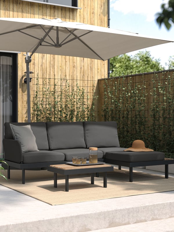 Un quitasol SVALÖN detrás de un sofá de terraza REVSKÄR .