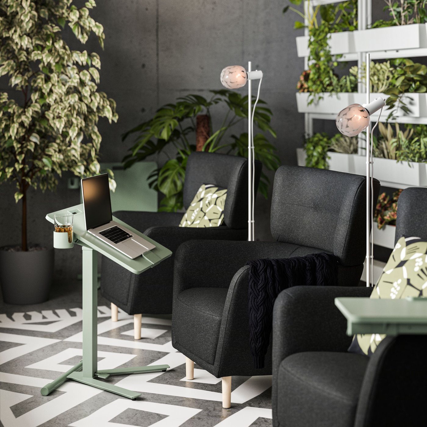 Tre lænestole og et MITTZON klapbord med hjul til bærbar computer er omgivet af grønt i et rum med betonvægge.