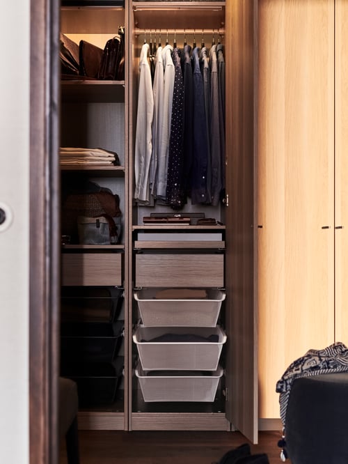Close-up on classic wardrobe combination with open door showing clothes on hangers and mesh baskets for accessories.