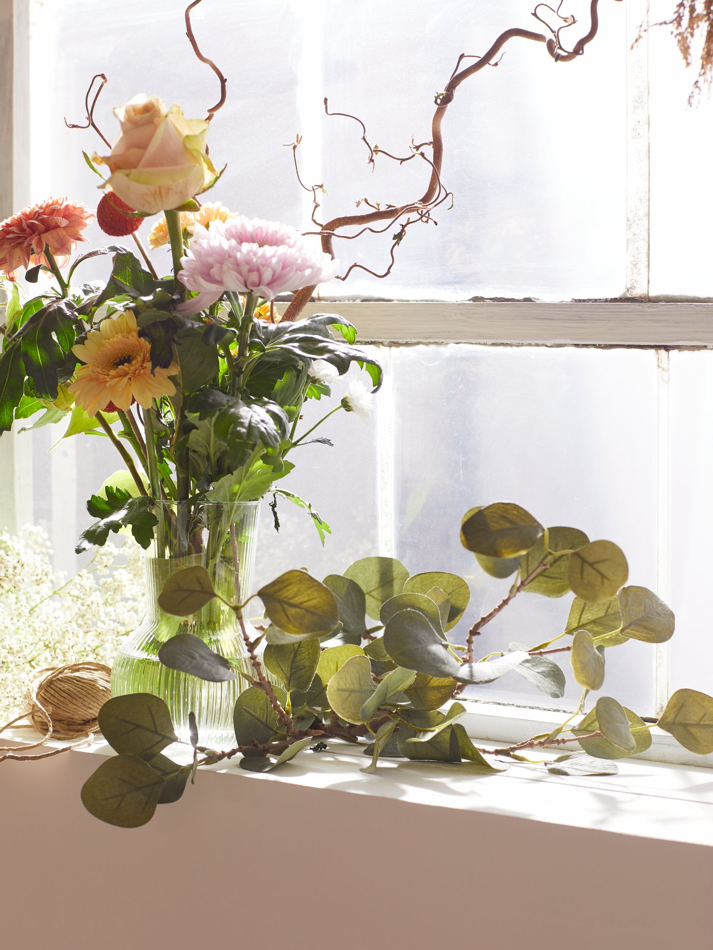 En vas med blommor står i ett fönster.