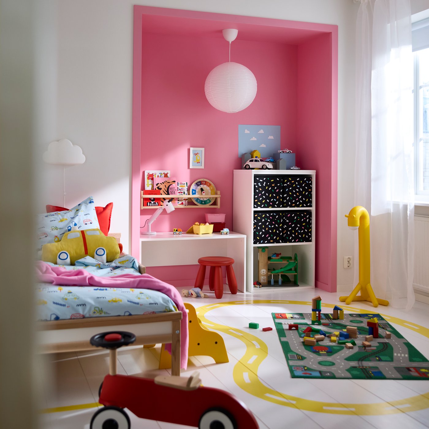 LASTARE wardrobe combination with shelves and patterned boxes in a children’s room with toys, play mat and pink accent wall.