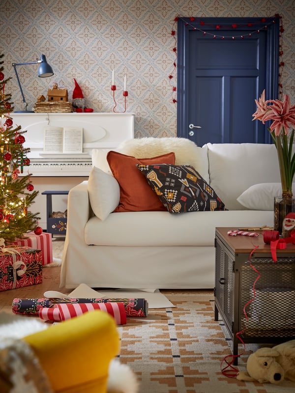 Weißes 2-Sitzer-Schlafsofa HYLTARP mit auffälligen Kissen in einem weihnachtlich dekorierten Wohnzimmer mit traditionellem schwedischem Thema.