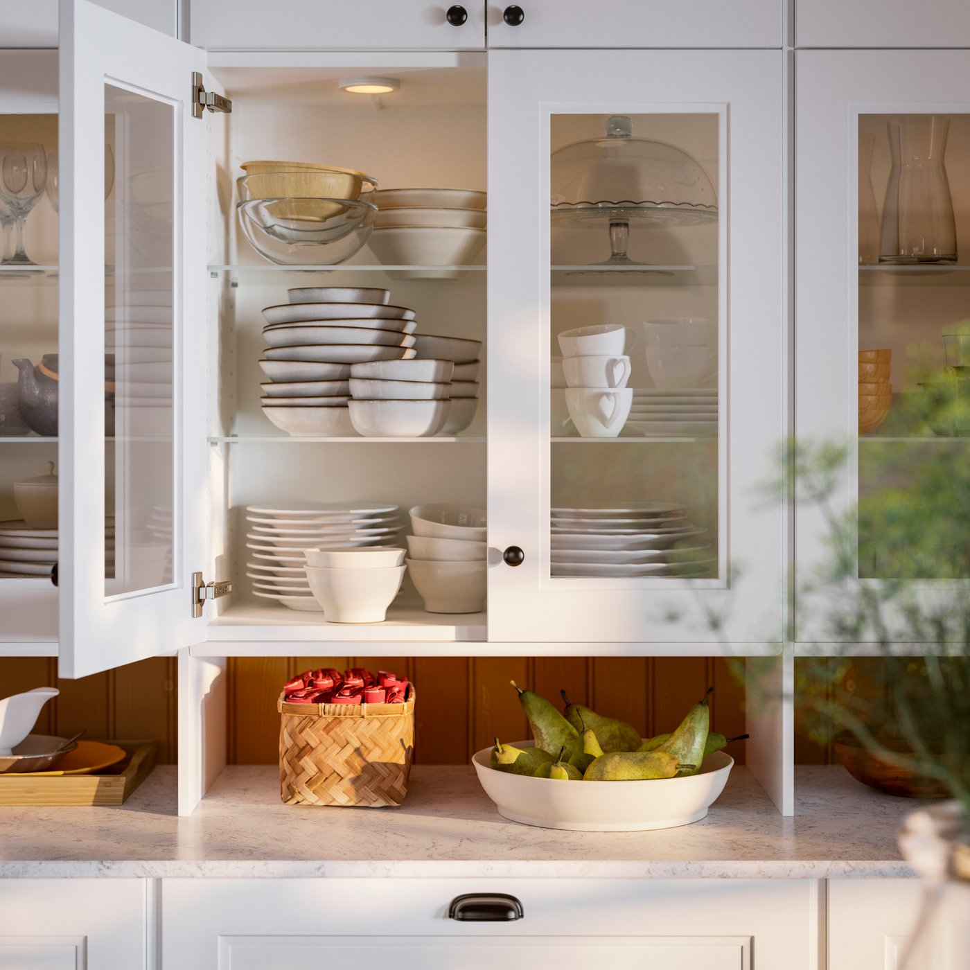 A white kitchen cabinet displays neatly arranged dishware, with bowls, plates, and glassware visible behind glass doors.