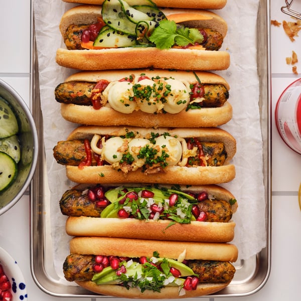 REFRÄNG vegetable hot dogs in buns on a metal tray are topped with ALLEMANSRÄTTEN mashed potatoes and other ingredients.