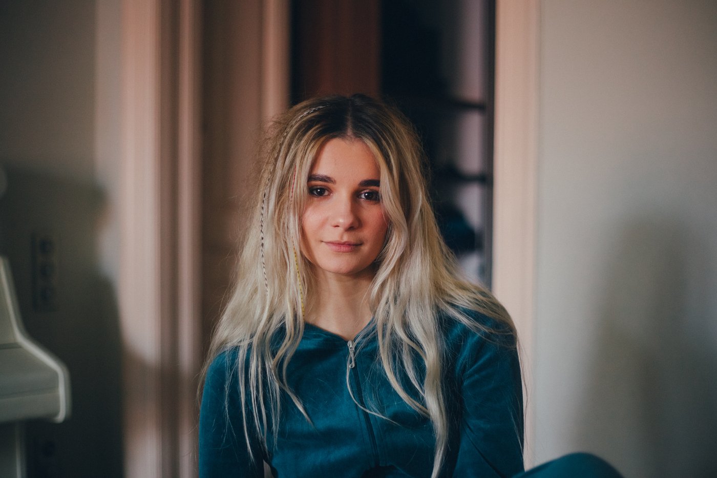 Yana at home wearing a green hoodie, she has some tiny braids in her hair.