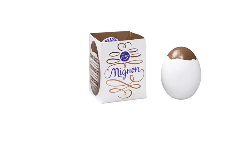Ein Mignon Ei aus Schokolade in einer echten Eierschalre - einmal in der Verpackung und rechts daneben ein augepacktes Mignon Ei.