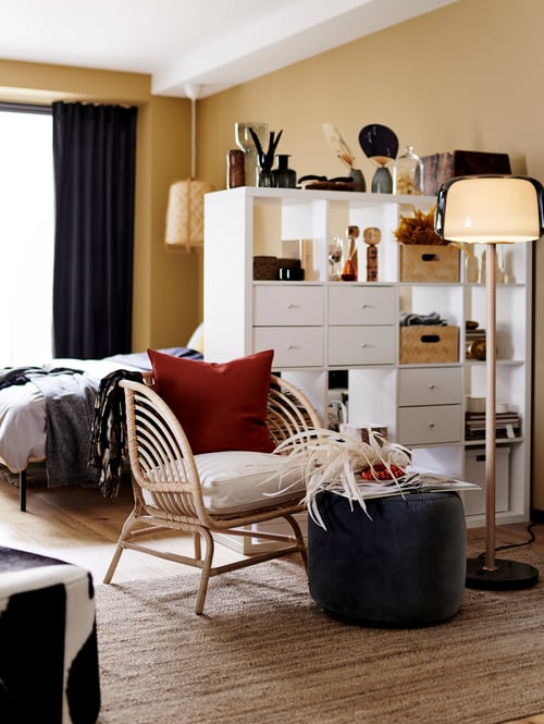 Cameră de zi cu etajeră, pouffe, fotoliu, lampadar, husă pentru pernă, covor, lampadar, pat, set de lenjerie de pat, cutii.