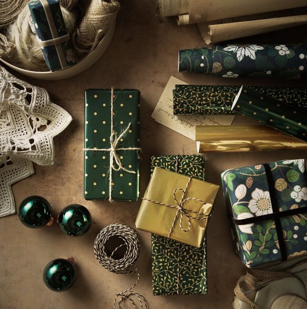 A selection of green and gold baubles, accessories and presents wrapped in VINTER 2020 paper and string.