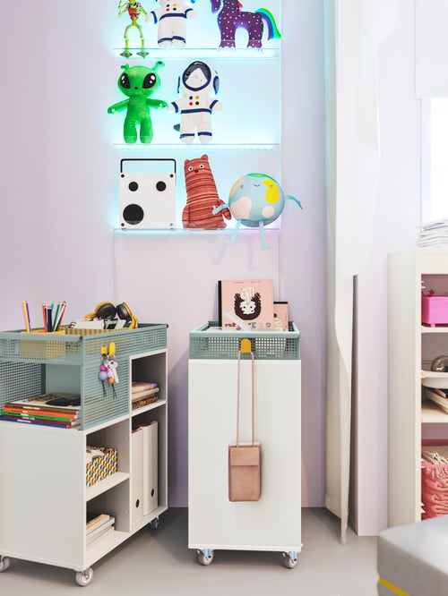 Kinderzimmer mit einem grauen ÖVNING Servierwagen, verschiedenen MELLÖSA Bilderleisten und AFTONSPARV Stoffspielzeug.