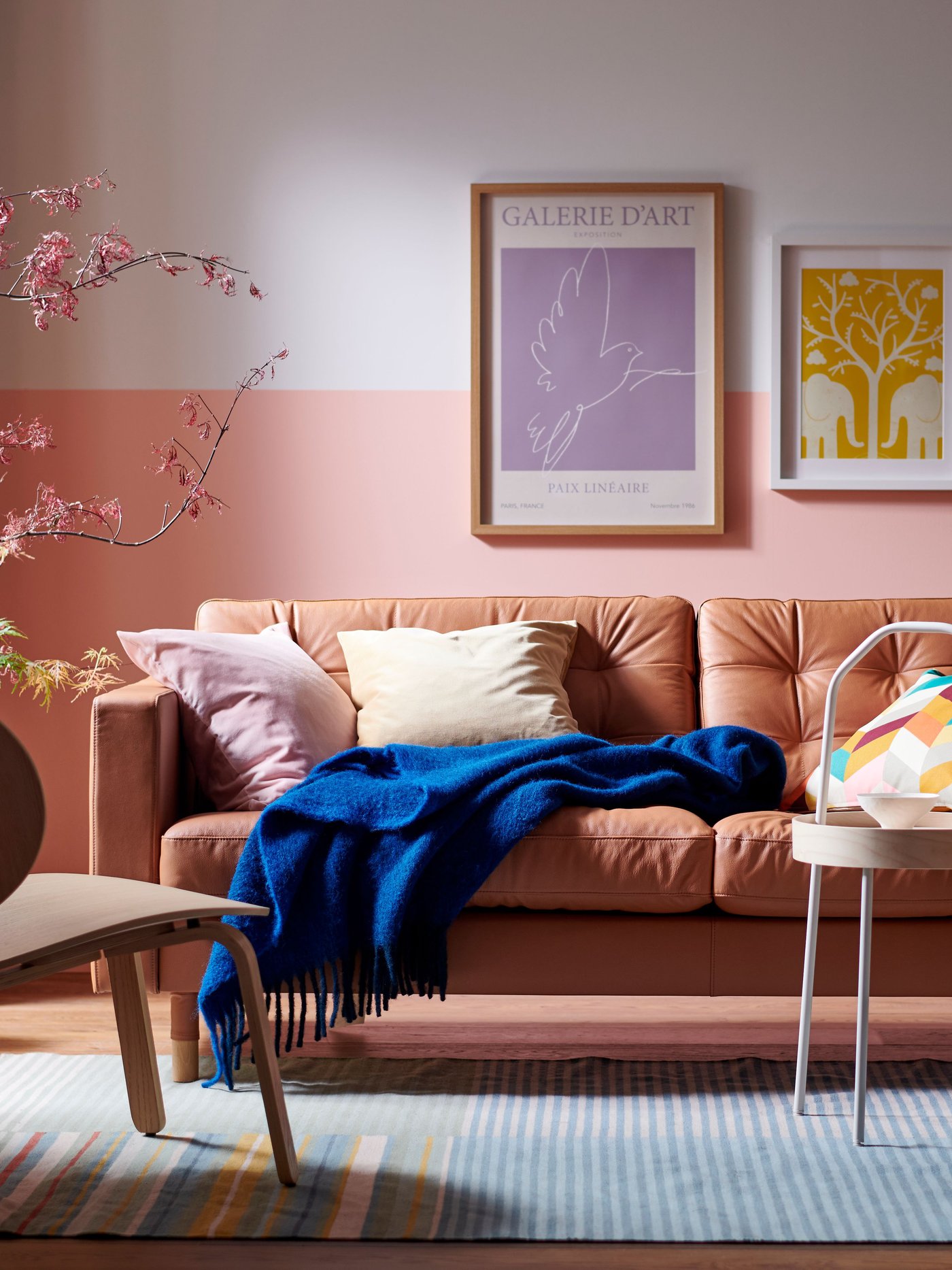 Ein LANDSKRONA-Sofa mit einer blauen KLIPPOXEL-Decke und zusätzlichen Kissen darauf und ein BURVIK-Beistelltisch stehen auf einem BUDDINGE-Teppich.