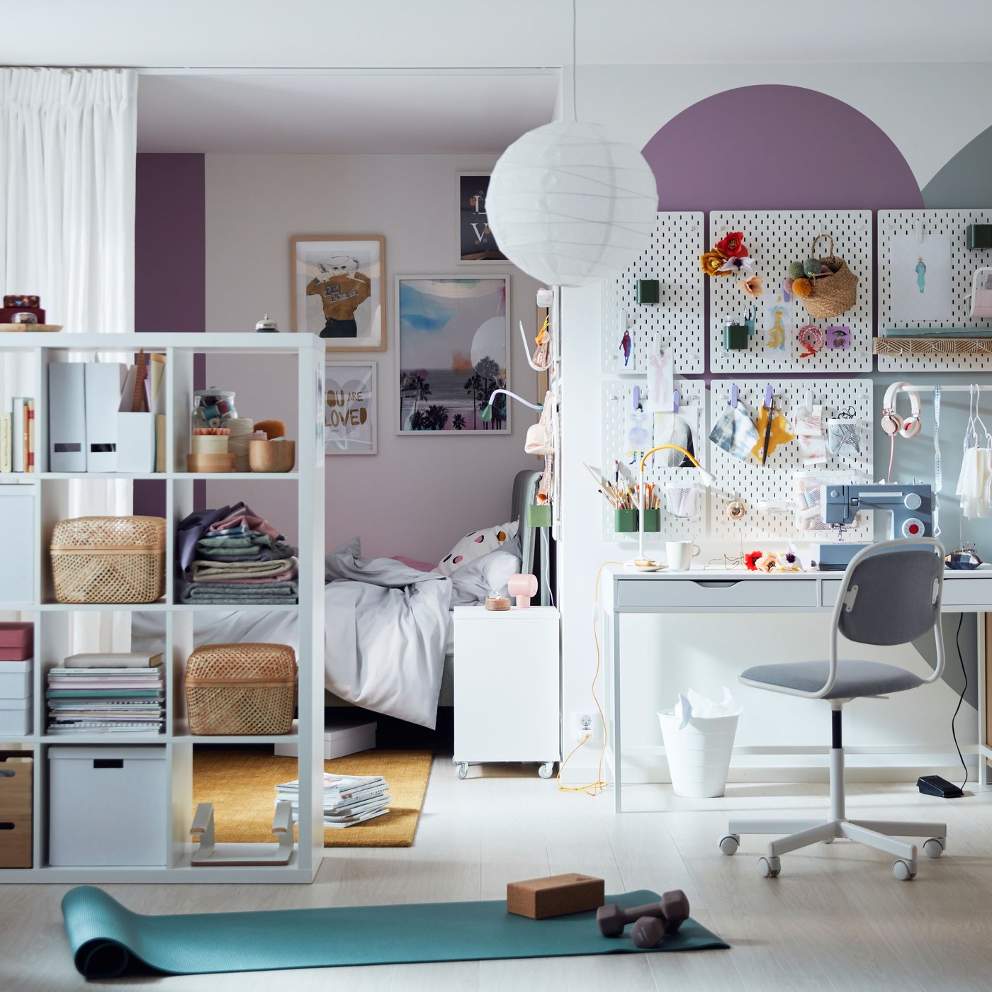 A bright, colourful room with pegboards over an ALEX desk, and curtains and a KALLAX shelving unit sectioning off a bed.