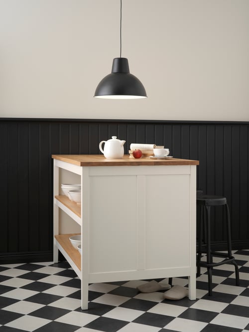 Dining room with a kitchen island on a tiled floor, with multiple bowls stored within, and a pendant lamp hanging above.