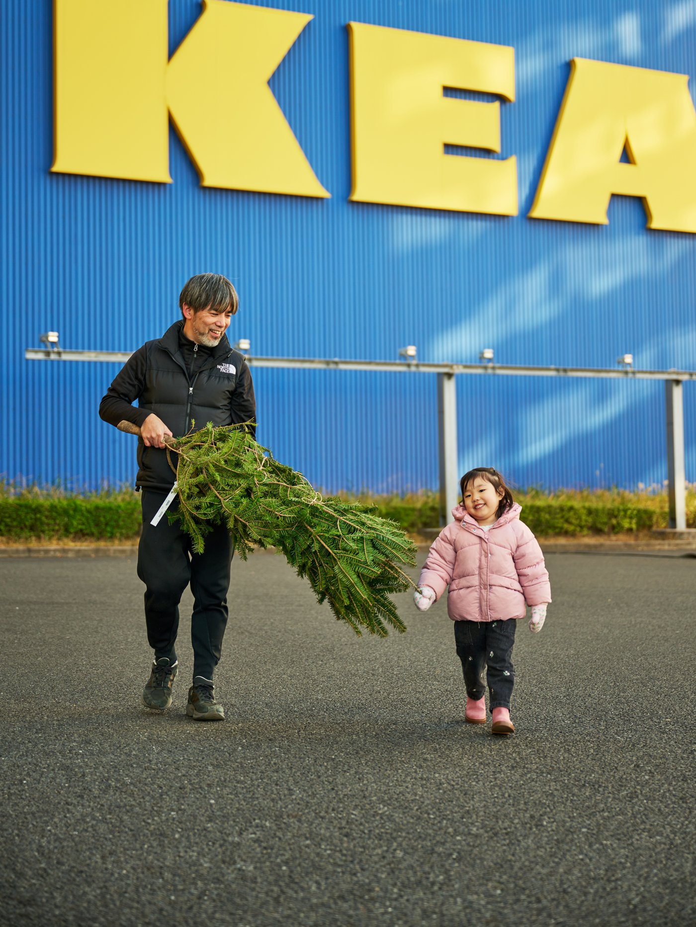 クリスマスツリーを運ぶ人物と横を歩く子供