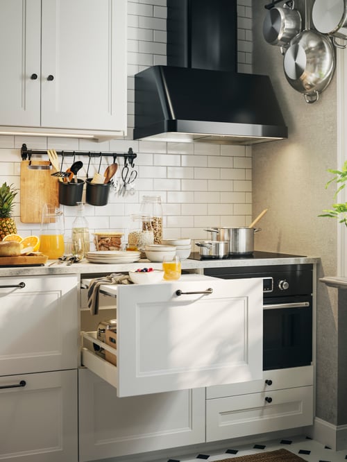 A kitchen with white AXSTAD drawer fronts, a wall mounted hood, a HULTARP rail, a pot with lid, a jug and a jar with lid.