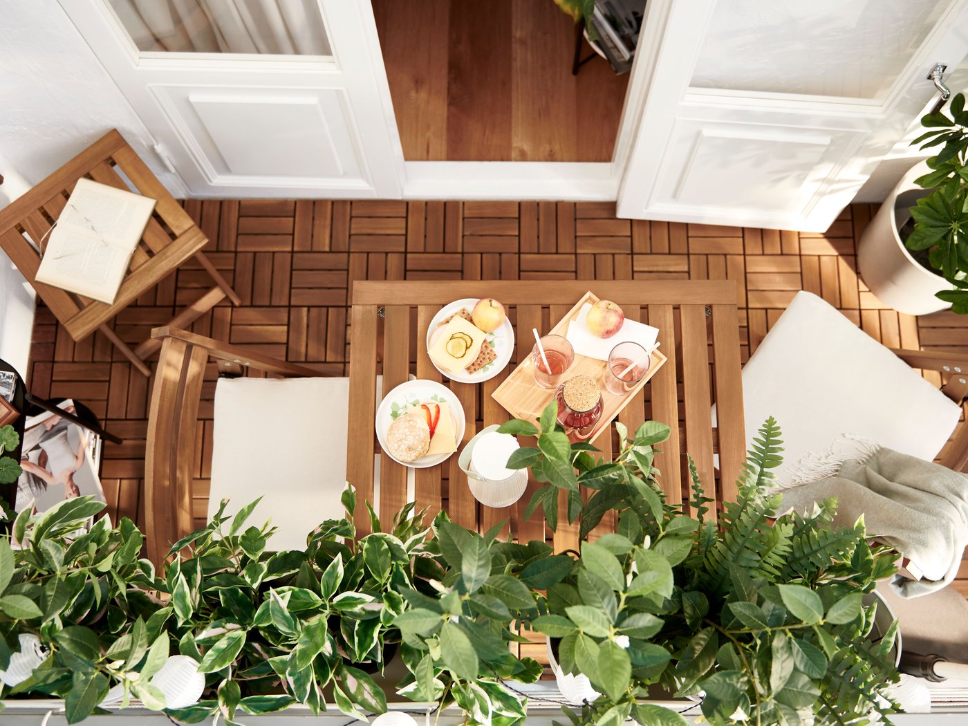 Balkon, který definují laťky akácie – u nábytku NÄMMARÖ a podlahové krytiny RUNNEN – a listnaté umělé rostliny FEJKA.