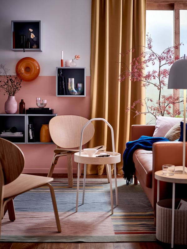 Two FRÖSET easy chairs and a BURVIK side table stand on a multicoloured BUDDINGE rug near a LANDSKRONA 3-seat sofa.
