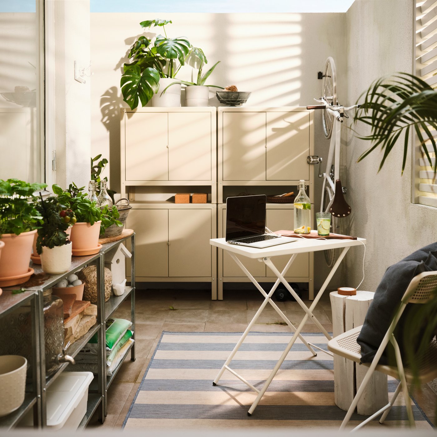 Sulla parete di un balcone, una soluzione di grandi dimensioni costituita da 2 mobili da interno/esterno KOLBJÖRN beige affiancati, sopra i quali sono impilati altri due mobili uguali.